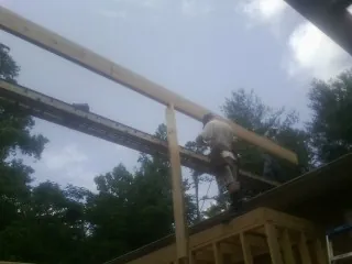 Carpenter setting a ridge beam over a new addition frame — Ice Dam Removal by Roofing Brothers in Thor