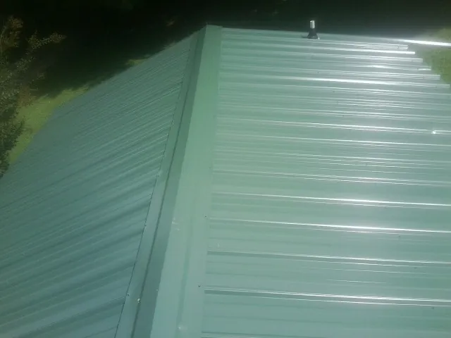 New green metal panels meeting at the ridge of a roof — Flat Roof Repair work by our crew in Thor