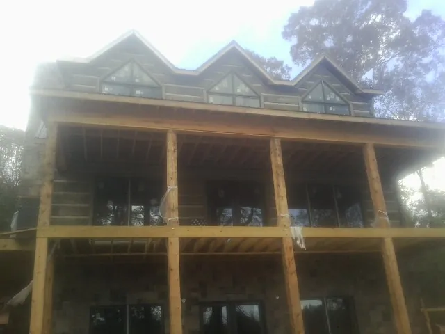 Dormers and porch framing on a large log home under construction — Roof Coating work by our crew in Thor
