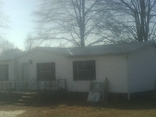 New metal roof on a white painted brick home on a foggy morning in Thor