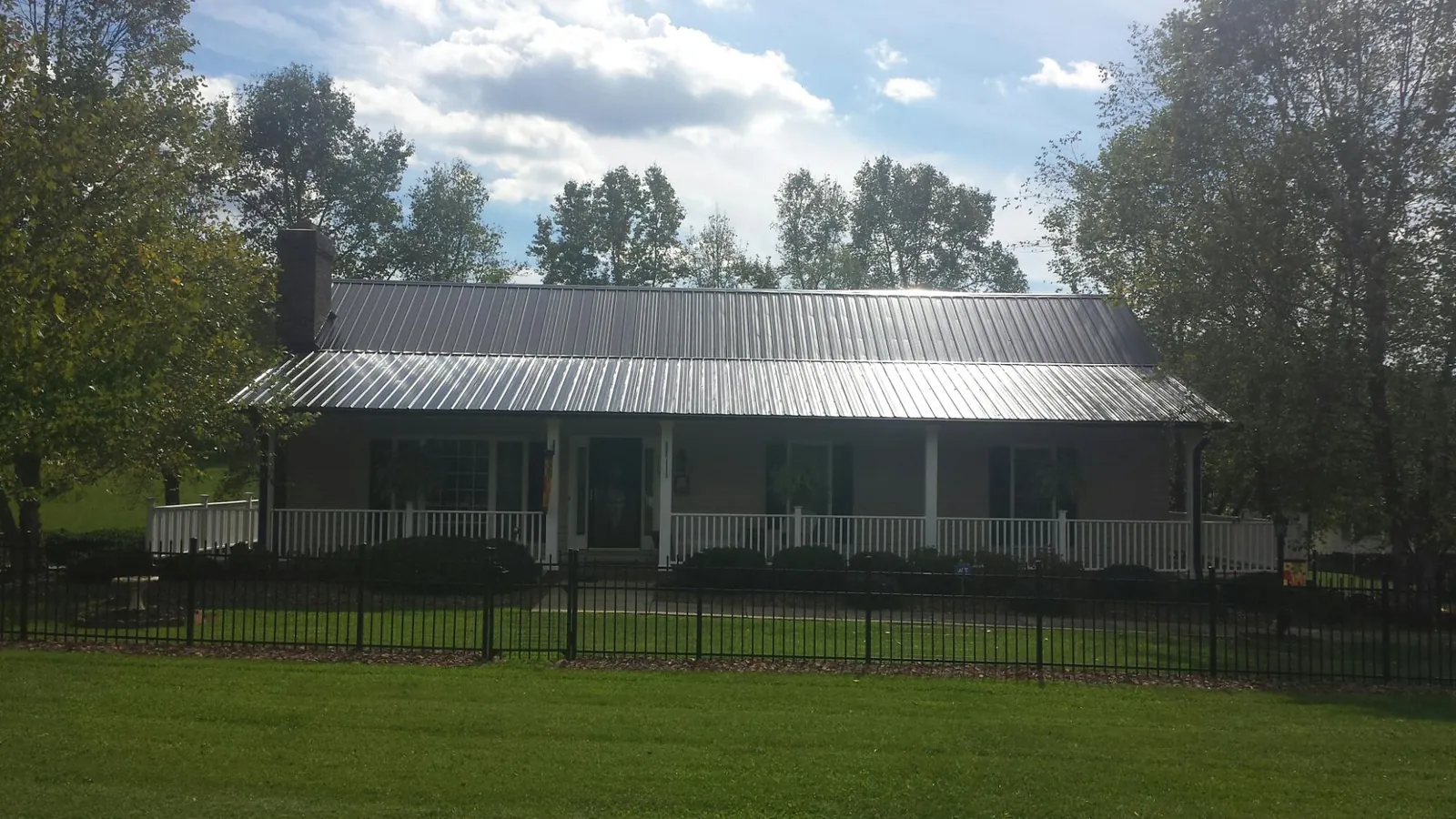 Gray metal roof on a brick ranch with a full width front porch — Gutter Guard Installation work by our crew in Thor