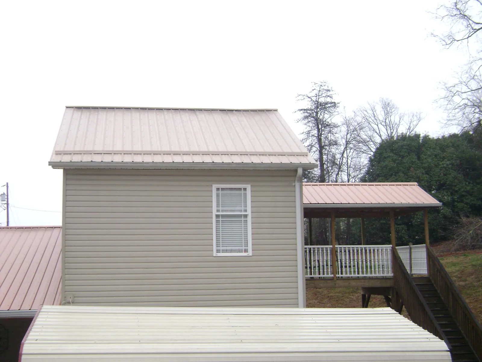 Tan metal roofs on a two story addition and attached porch, from a Roof Replacement job in Thor