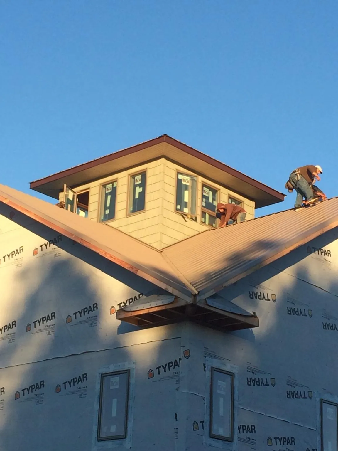 Roofers working around a rooftop cupola on a new metal roof at sunset — Roof Waterproofing in Thor by Roofing Brothers